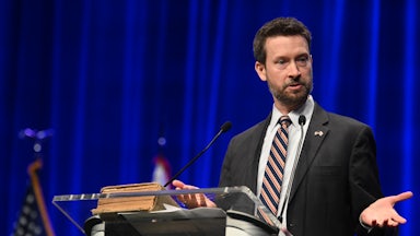Charles Allen gesticulates while speaking at a podium.