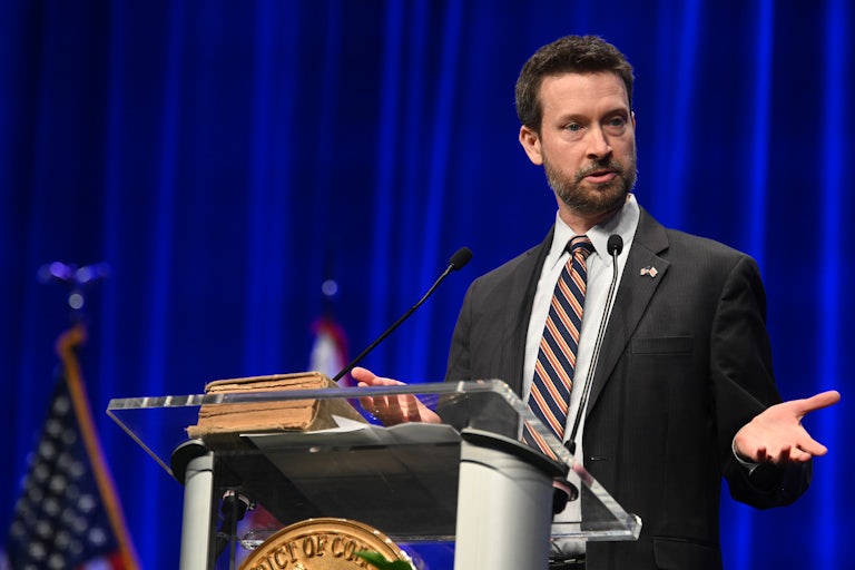 Charles Allen gesticulates while speaking at a podium.