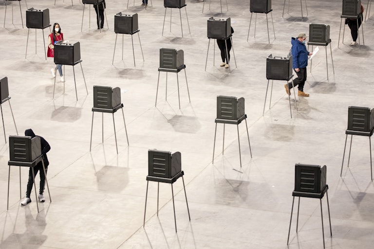 A few people stand amid a mass of empty polling booths.