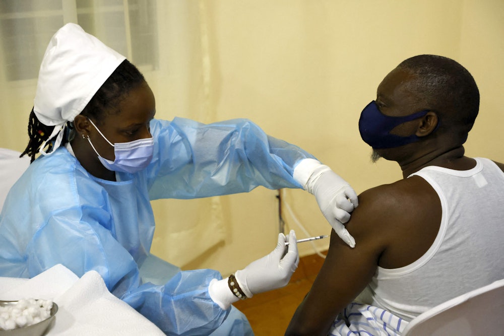 A medical worker injects a shot into a patient's left arm.