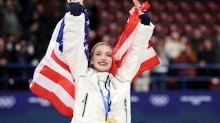 Amber Glenn holds up a U.S. flag as she celebrates at the Olympics.