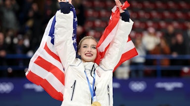 Amber Glenn holds up a U.S. flag as she celebrates at the Olympics.