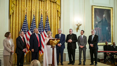 Paula Cain-White speaks at the White House Easter lunch on stage with several others, including President Trump.