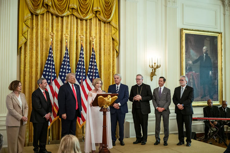 Paula Cain-White speaks at the White House Easter lunch on stage with several others, including President Trump.