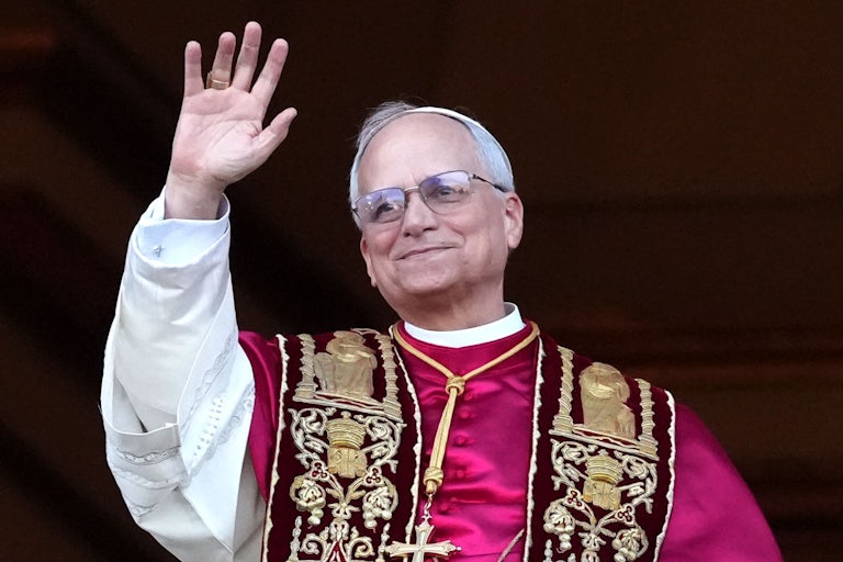 Pope Leo XIV waves while standing on the balcony of the Vatican