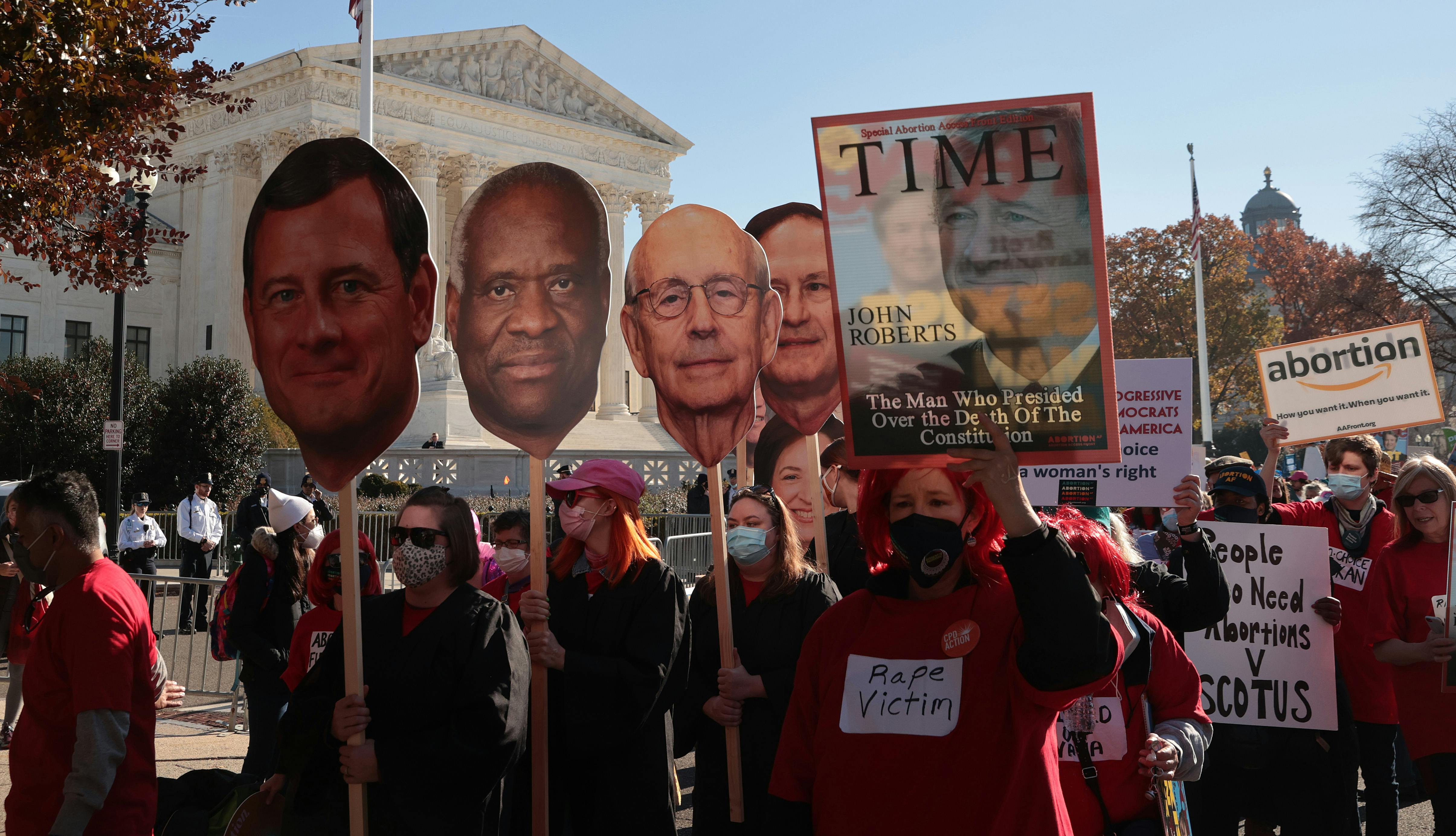Demonstrators carry large cut-outs of the heads of the Supreme Court's justices during a protest.