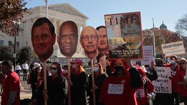 Demonstrators carry large cut-outs of the heads of the Supreme Court's justices during a protest.