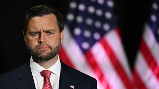 JD vance looks confused while standing in front of a US flag