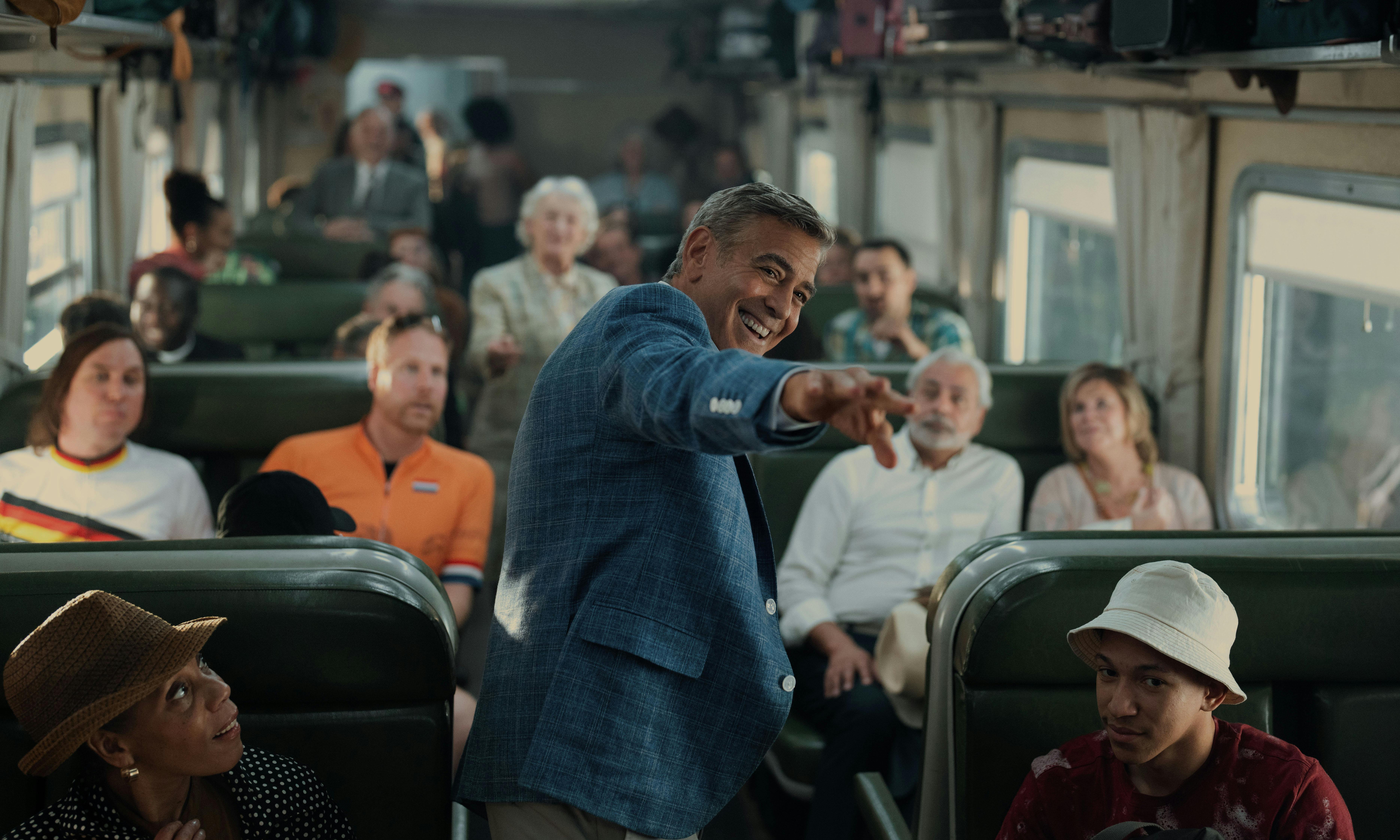 George Clooney standing in the aisle of a crowded train in Noah Baumbach’s “Jay Kelly”