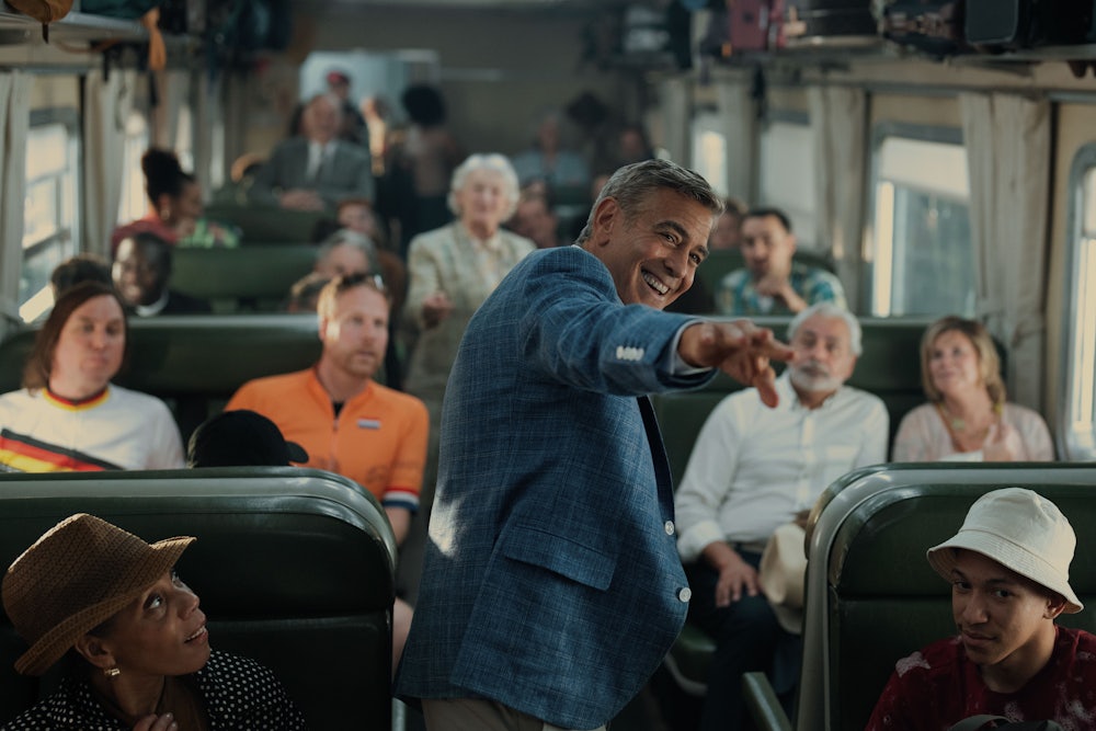 George Clooney standing in the aisle of a crowded train in Noah Baumbach’s “Jay Kelly”