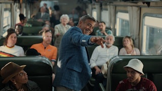 George Clooney standing in the aisle of a crowded train in Noah Baumbach’s “Jay Kelly”