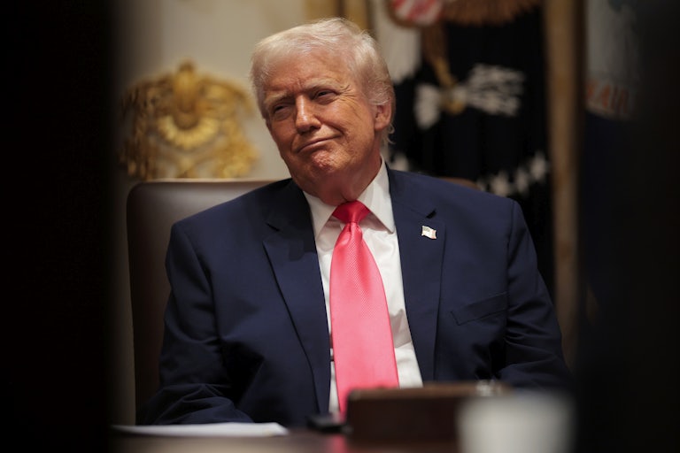 Donald Trump smiles while sitting in a Cabinet meeting
