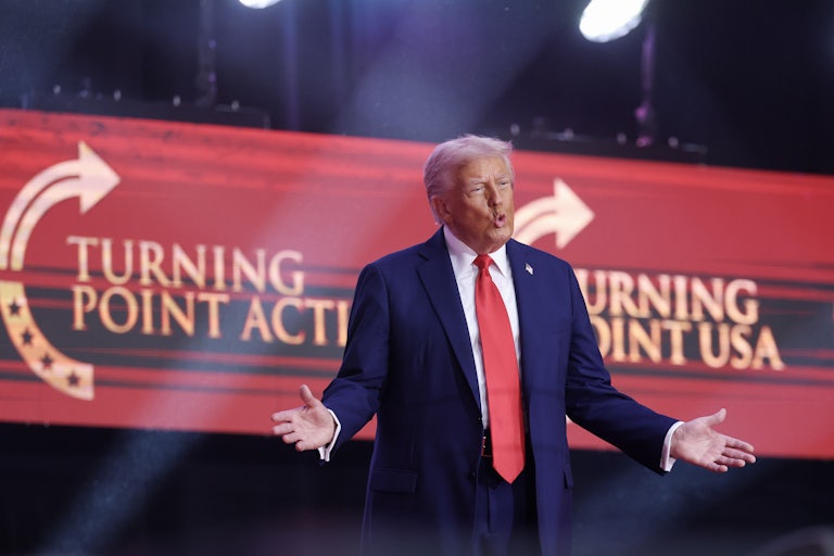 Donald Trump puckers his lips and holds his hands out to the side as he walks on stage at Charlie Kirk's memorial service