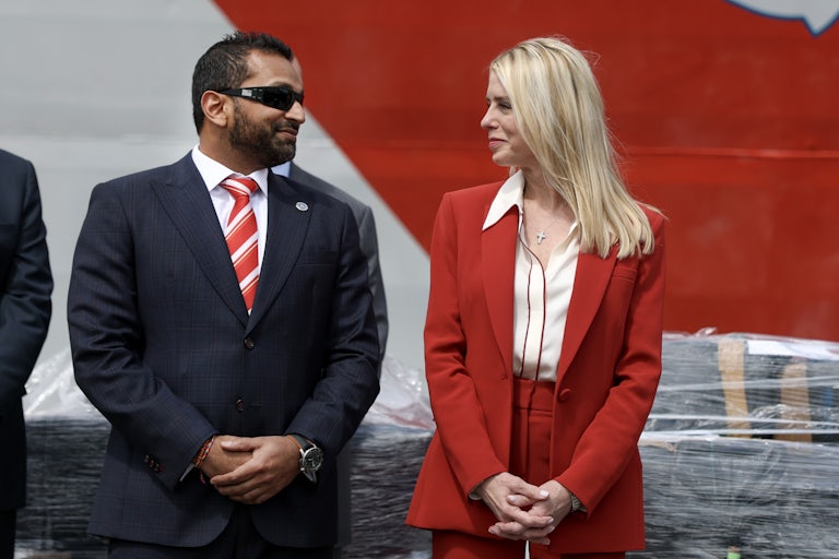 FBI Director Kash Patel and Attorney General Pam Bondi stand next to and smile at each other