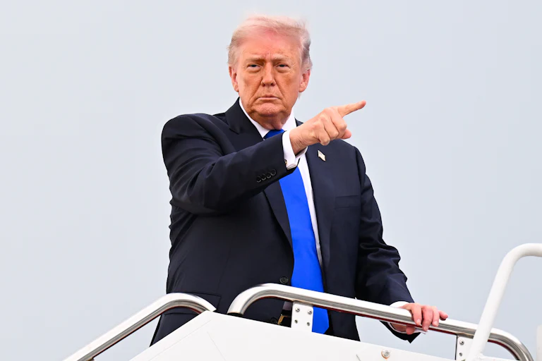 President Donald Trump board Air Force One and points into the distance.