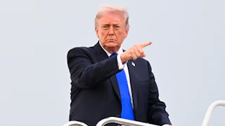 President Donald Trump board Air Force One and points into the distance.