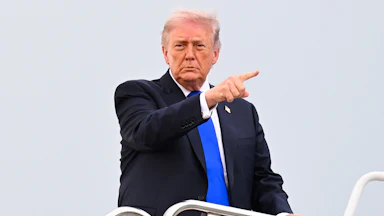 President Donald Trump board Air Force One and points into the distance.