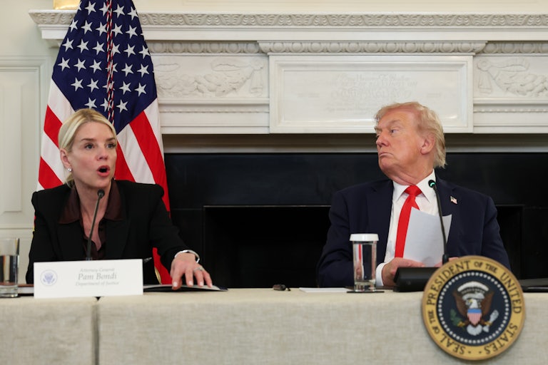 Donald Trump listens as Pam Bondi speaks, while both are seated at a table.