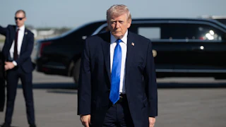Donald Trump stands on an airport tarmac