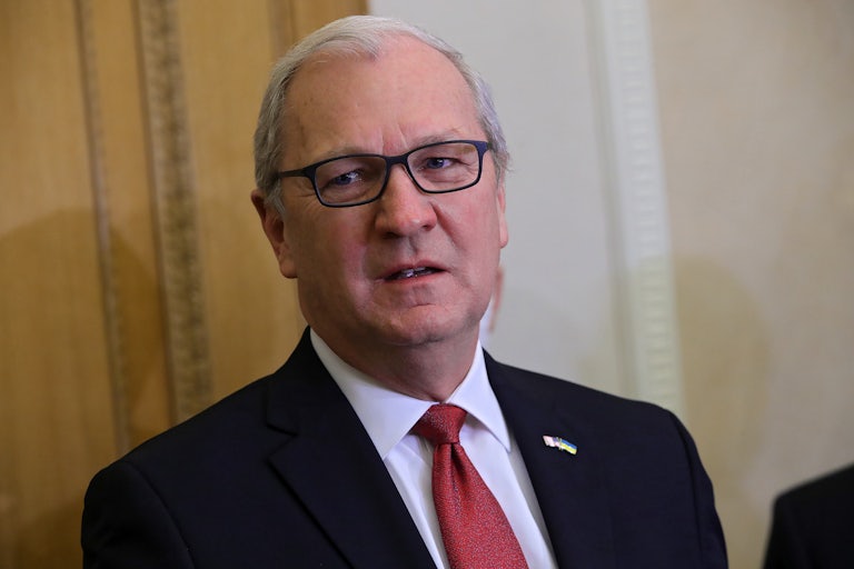 Senator Kevin Cramers wears a black suit, red tie, and black glasses. He looks off camera.