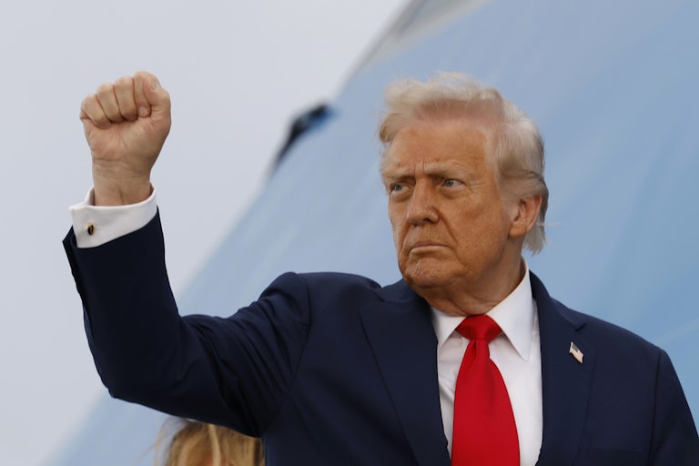 Donald Trump raises his fist while boarding Air Force One