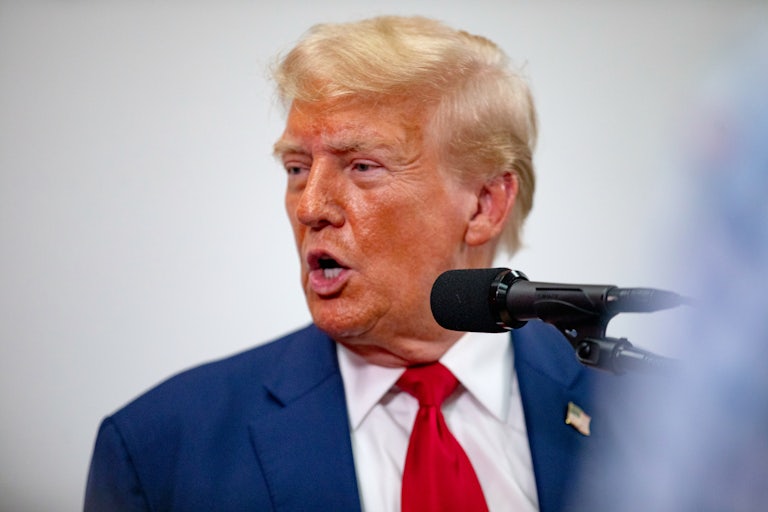 Donald Trump yells and turns his head. A mic is in front of him.