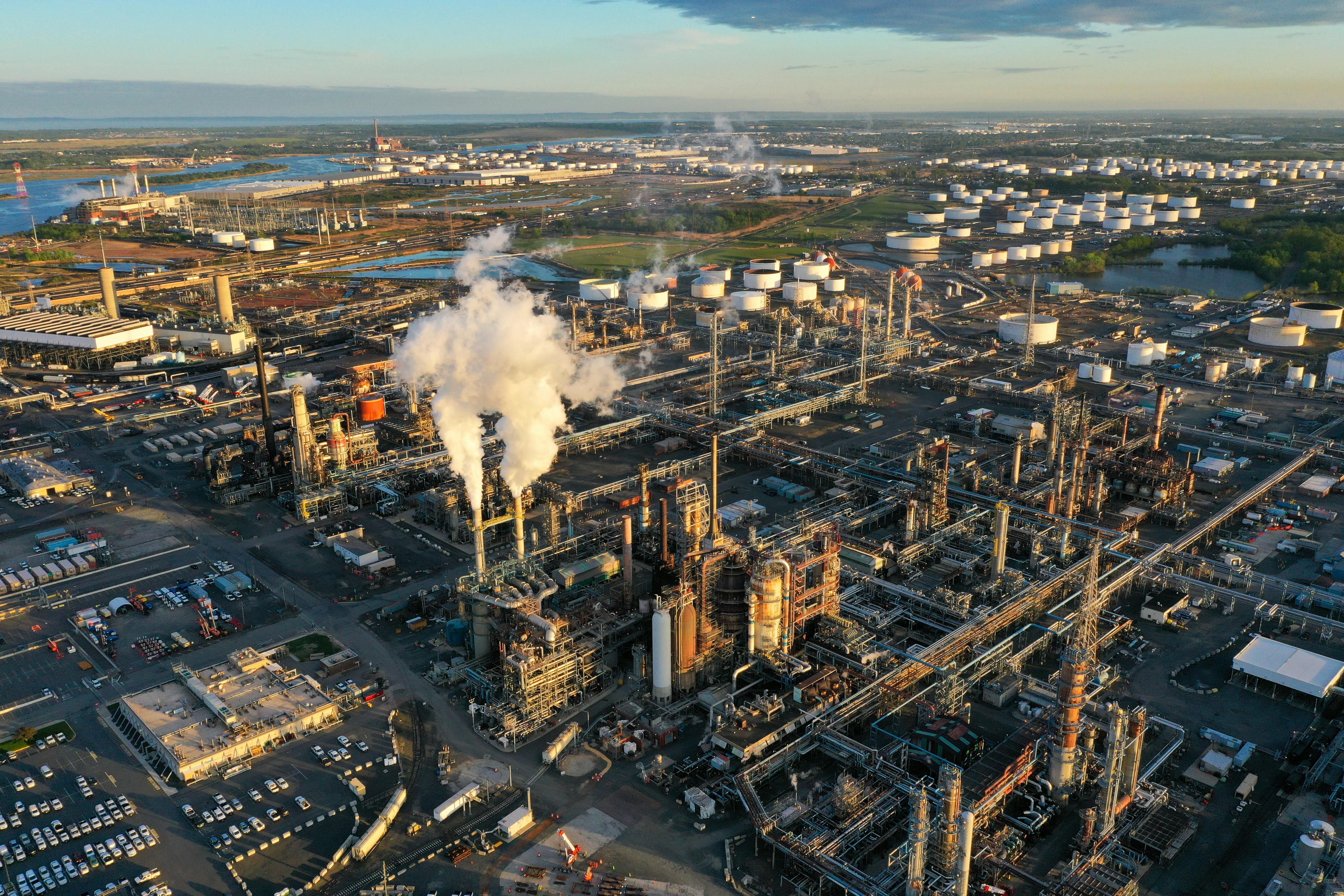 A refinery with smokestacks sits near a river.