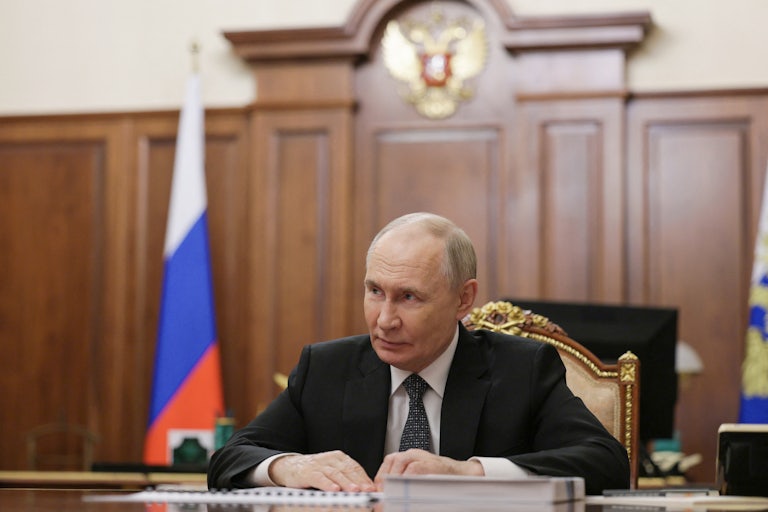 Russian President Vladimir Putin sits in a meeting
