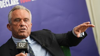Robert F. Kennedy Jr. speaks, holding a mic with one hand and making a hand gesture with the other