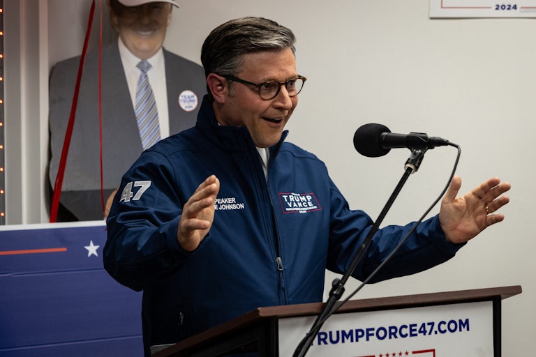 Mike Johnson gestures and smiles while speaking at a Donald Trump campaign event