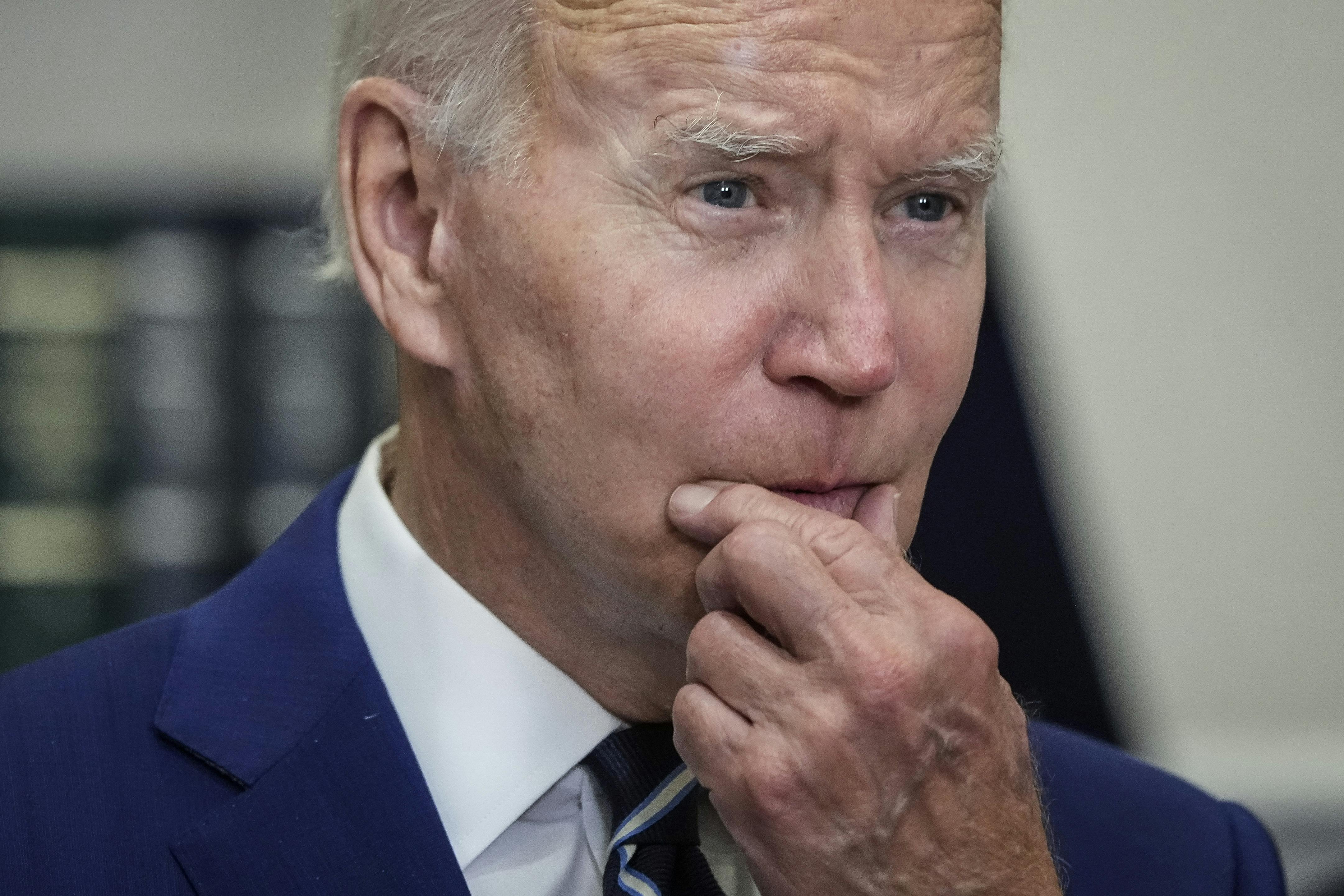 President Joe Biden strokes his chin.