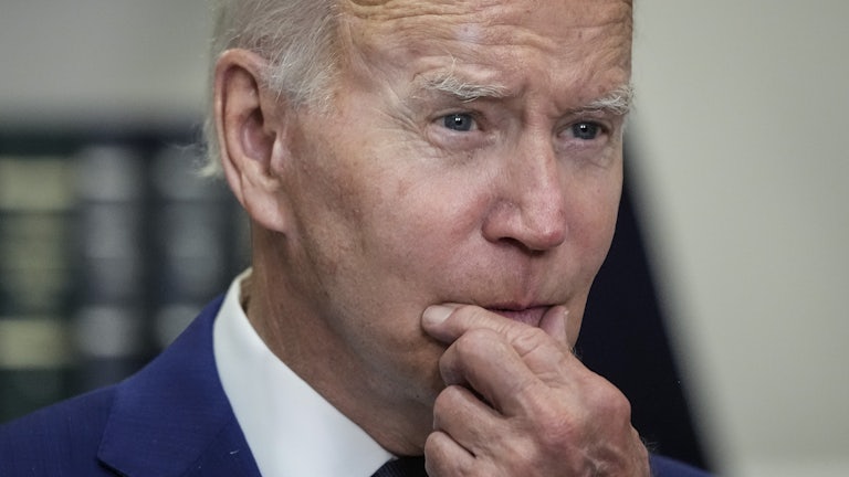 President Joe Biden strokes his chin.