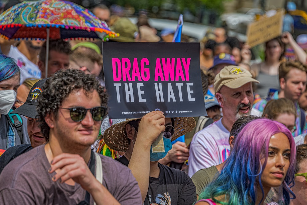 Someone holds a sign "drag away the hate" in a crowd of people.