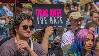 Someone holds a sign "drag away the hate" in a crowd of people.