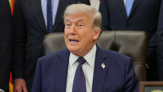 Donald Trump speaks while sitting at his desk in the Oval Office
