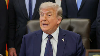 Donald Trump speaks while sitting at his desk in the Oval Office
