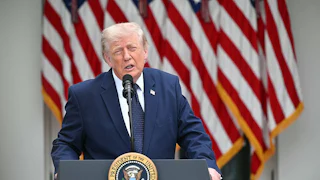 Donald Trump stands at a podium and squints