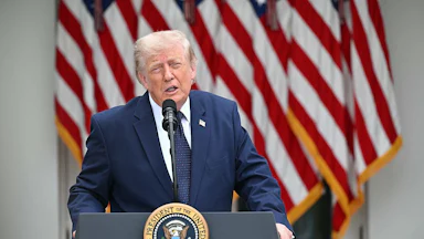 Donald Trump stands at a podium and squints