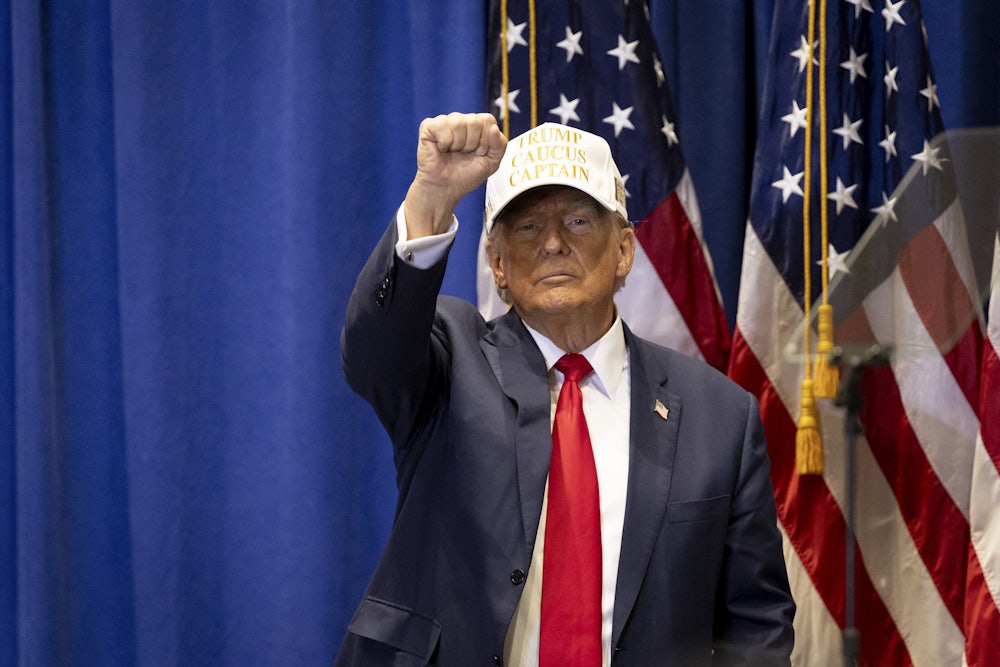 Donald Trump raises his first while wearing a baseball cap.