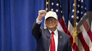 Donald Trump raises his first while wearing a baseball cap.