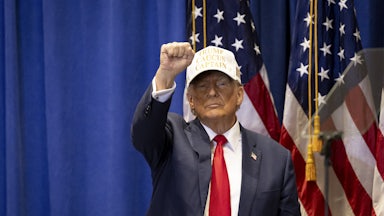 Donald Trump raises his first while wearing a baseball cap.