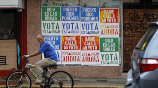 A man rides his bicycle in front of a wall covered with campaign posters promoting Puerto Rico’s statehood