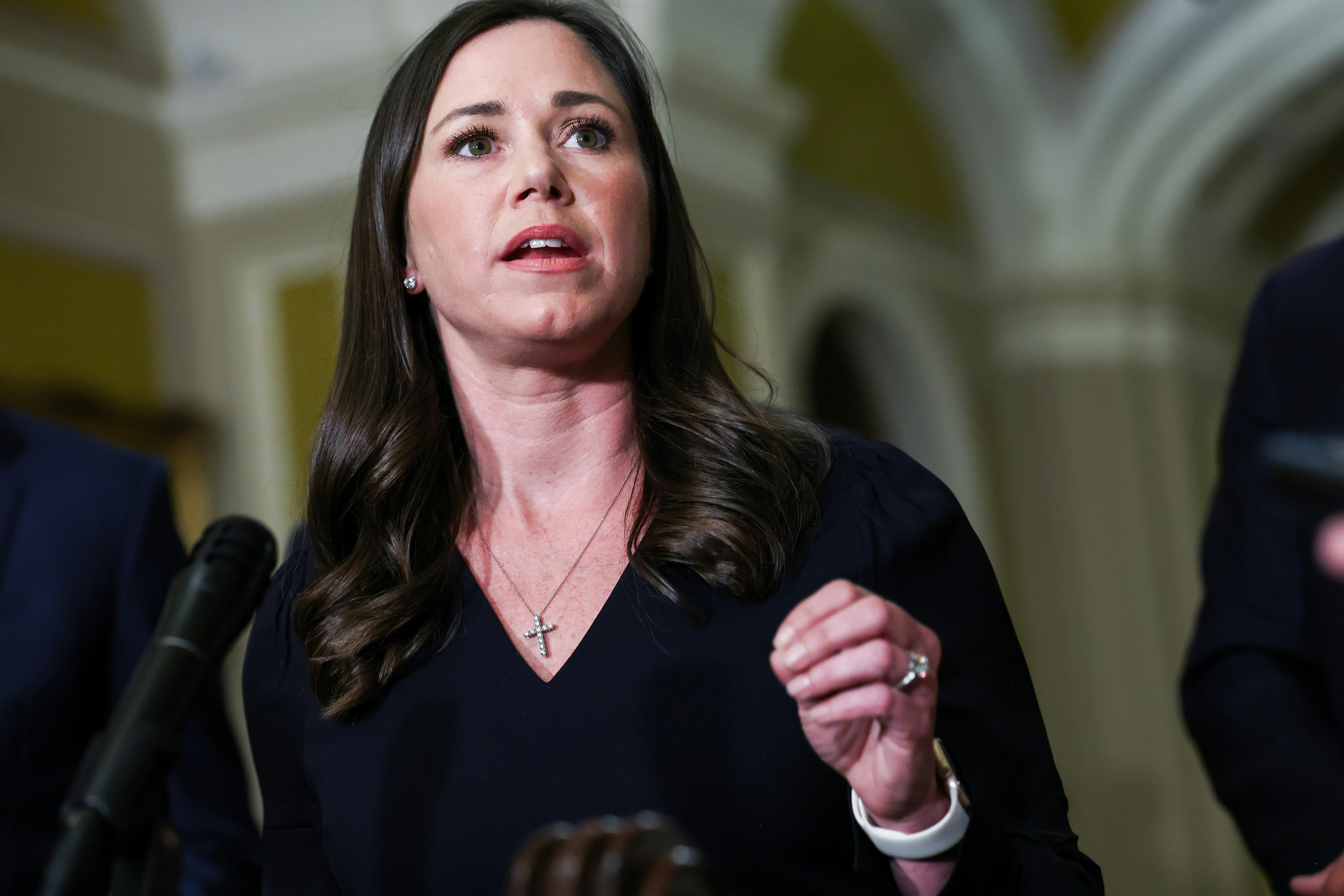Senator Katie Britt gestures while speaking at a podium