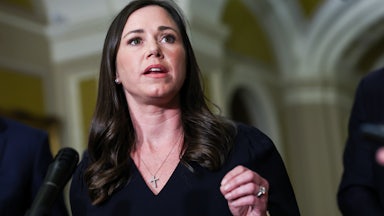 Senator Katie Britt gestures while speaking at a podium