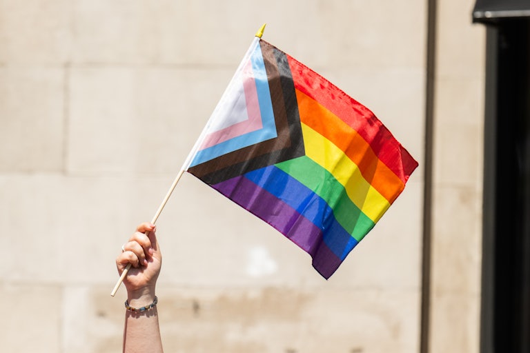 A person holds up a rainbow LGBTQ flag during a Pride parade