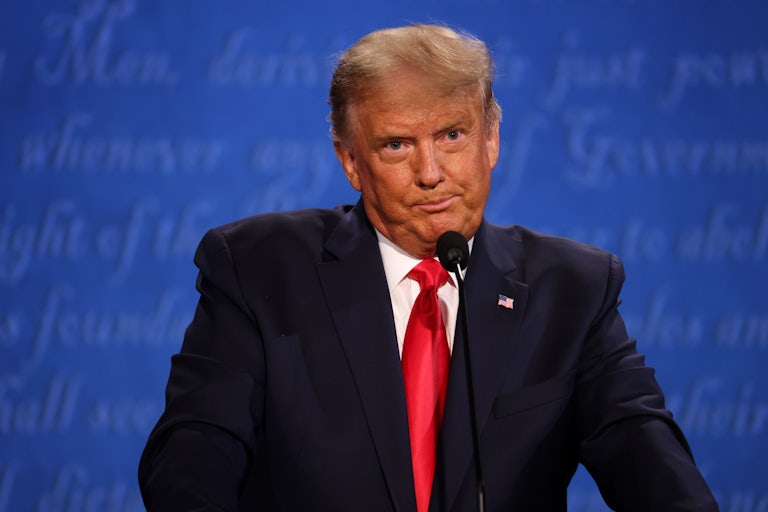 Donald Trump purses his lips while standing at a microphone