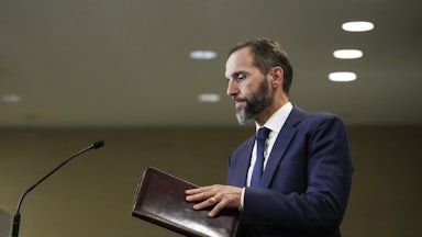 Special counsel Jack Smith holds a folder and walks toward a podium.