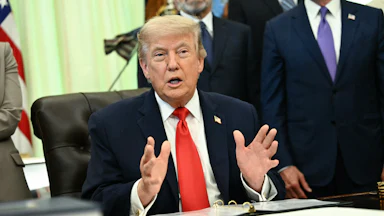 President Donald Trump speaking at his desk in the Oval Office of the White House
