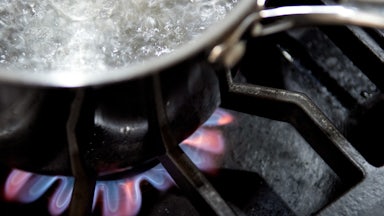 A pot with boiling water sits on a gas burner.