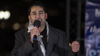 Mohsen Mahdawi speaks into a microphone during an event